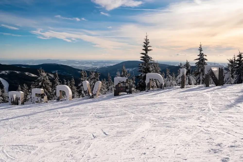 Pistenavn Medvedin i store bogstaver på toppen af Spindleruv Mlyn, med bjergpanorama i baggrunden